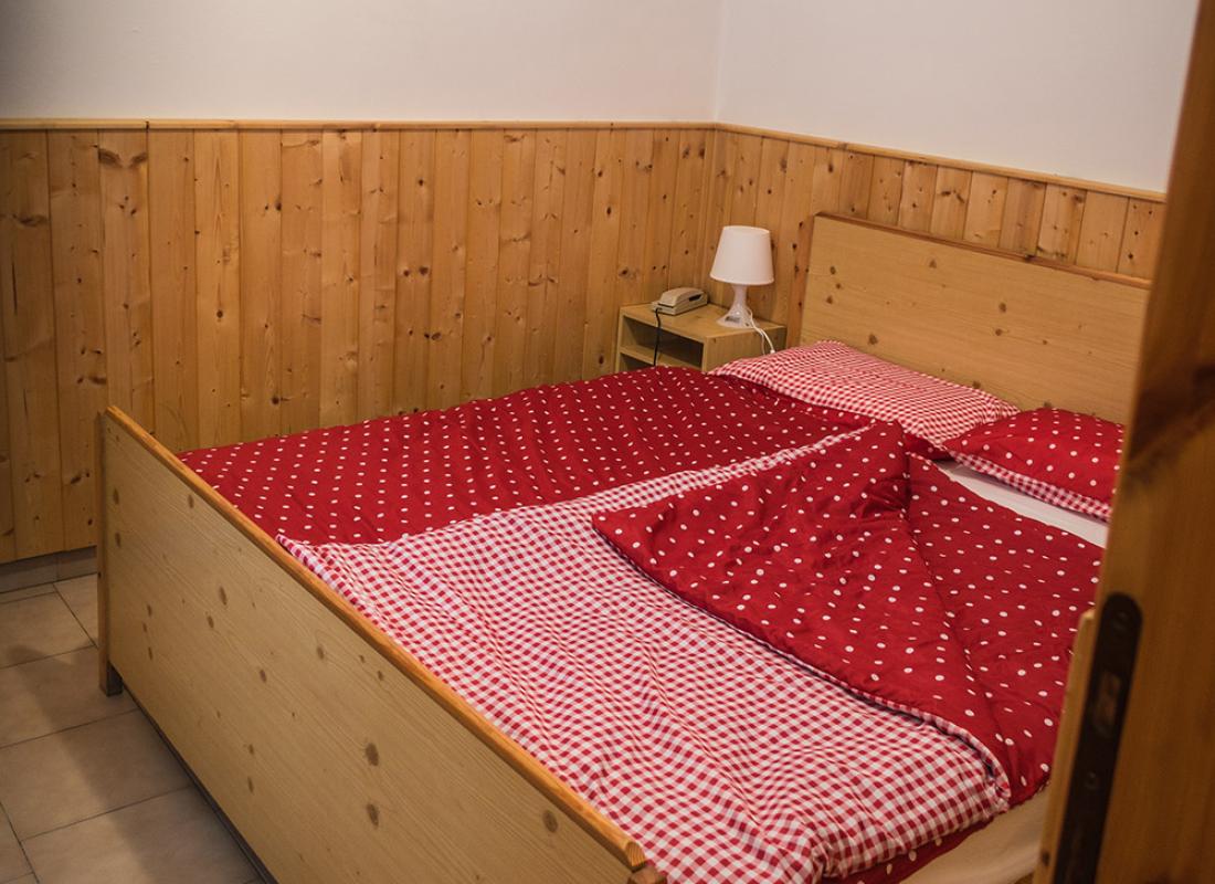 Camera da letto con letto in legno e biancheria rossa a pois.