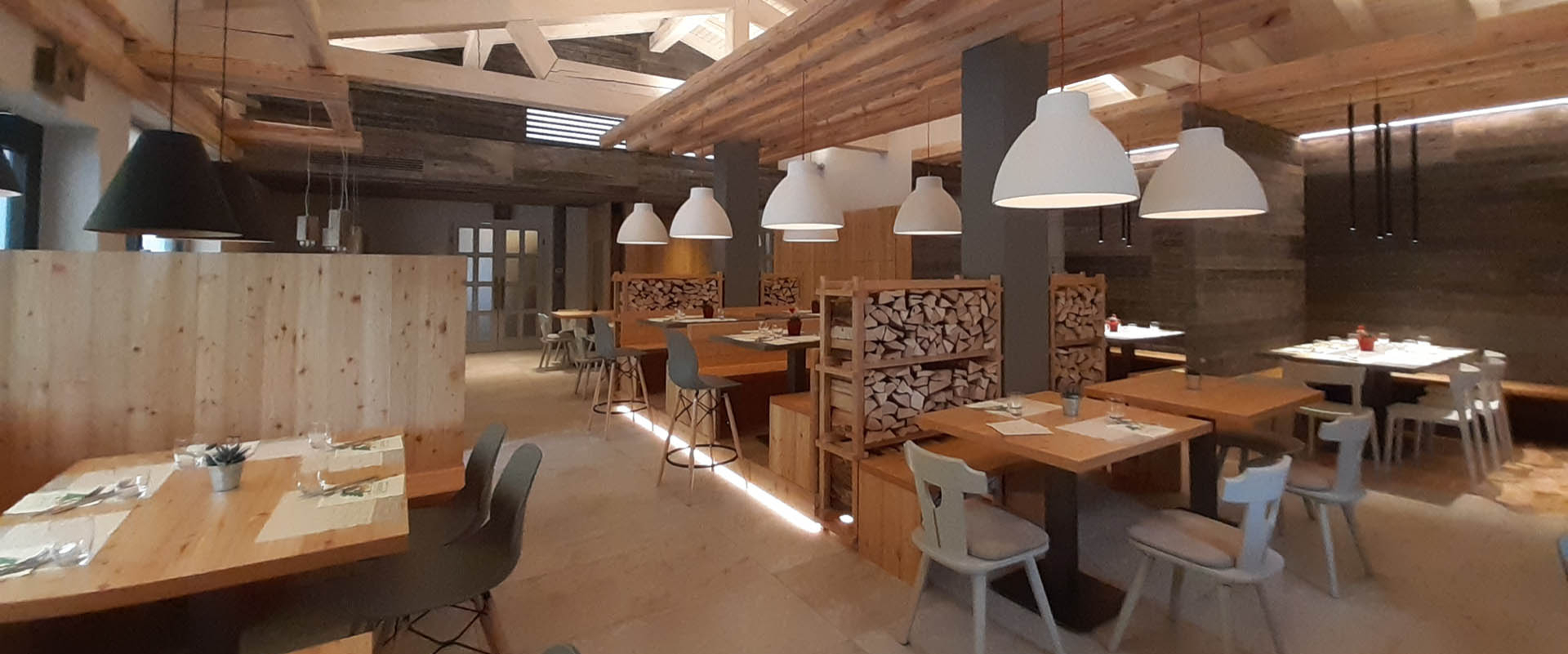 Ristorante moderno con arredi in legno, illuminazione soffusa e atmosfera accogliente.
