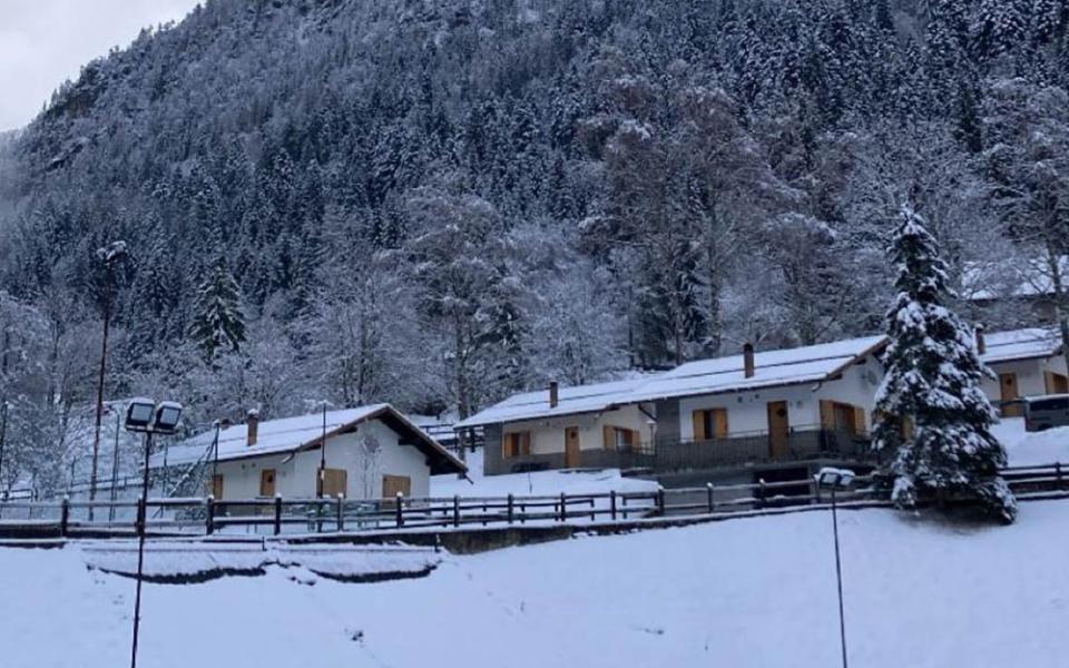 Snow-covered chalets at the foot of a mountain.
