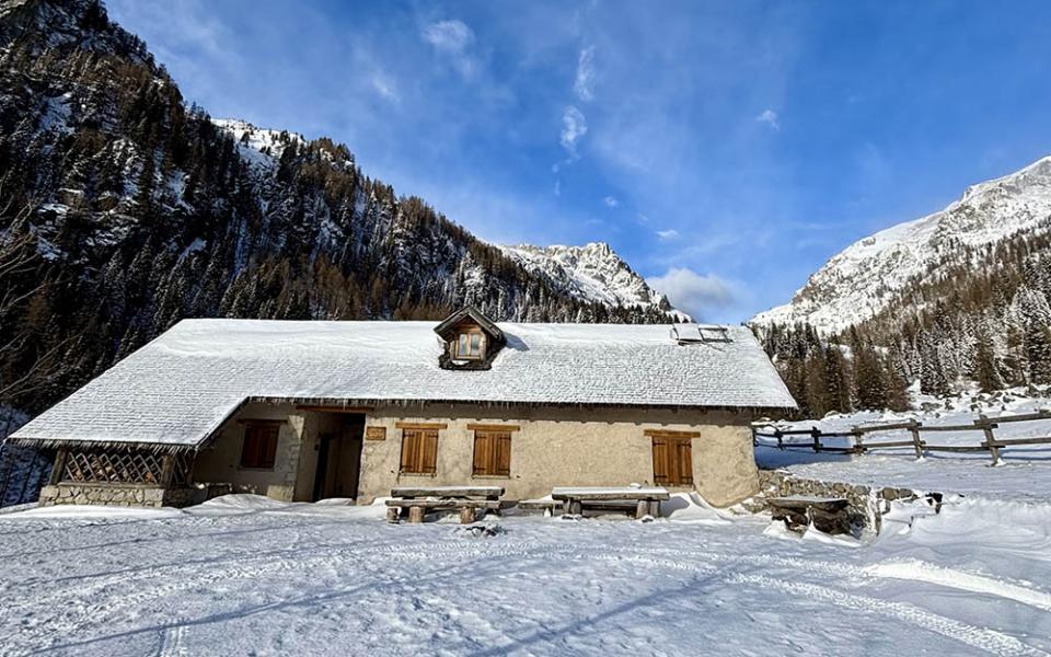 Parco giochi innevato con montagne e alberi, atmosfera invernale serena.