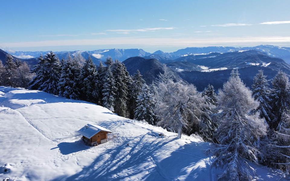 Montagna innevata illuminata dal sole al tramonto, cielo sereno e azzurro.