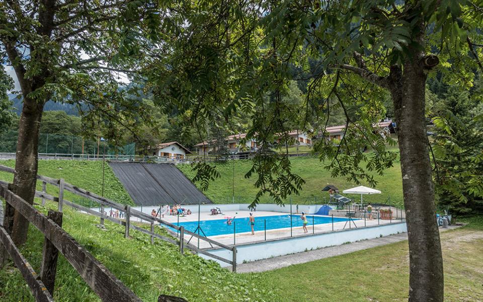 Freibad umgeben von Bäumen und grünen Hügeln.