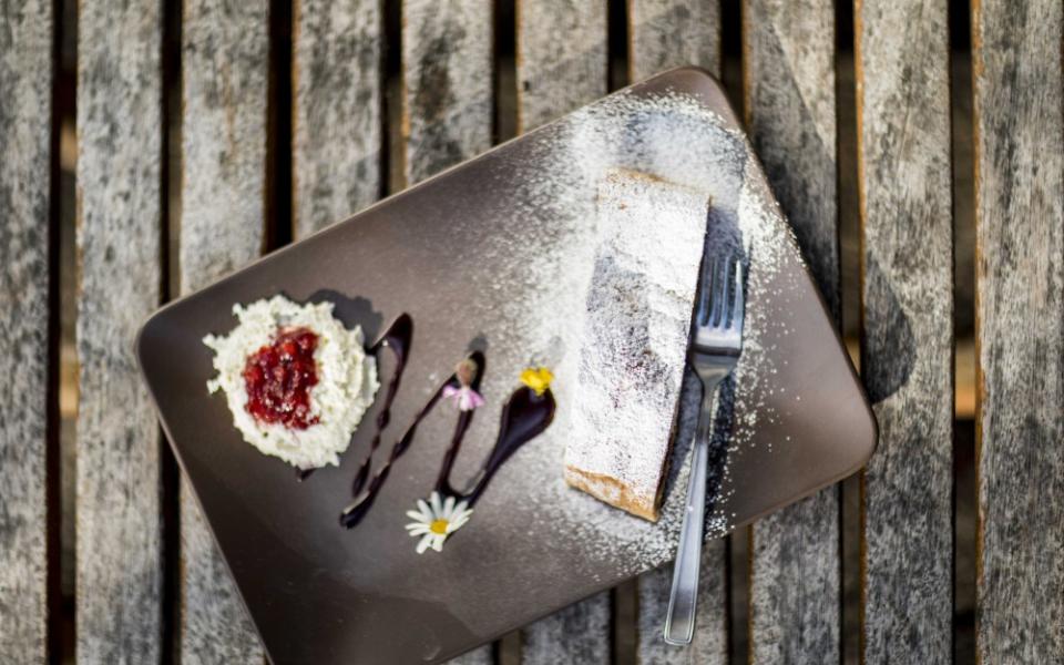 Dolce con zucchero a velo e panna montata su piatto scuro.
