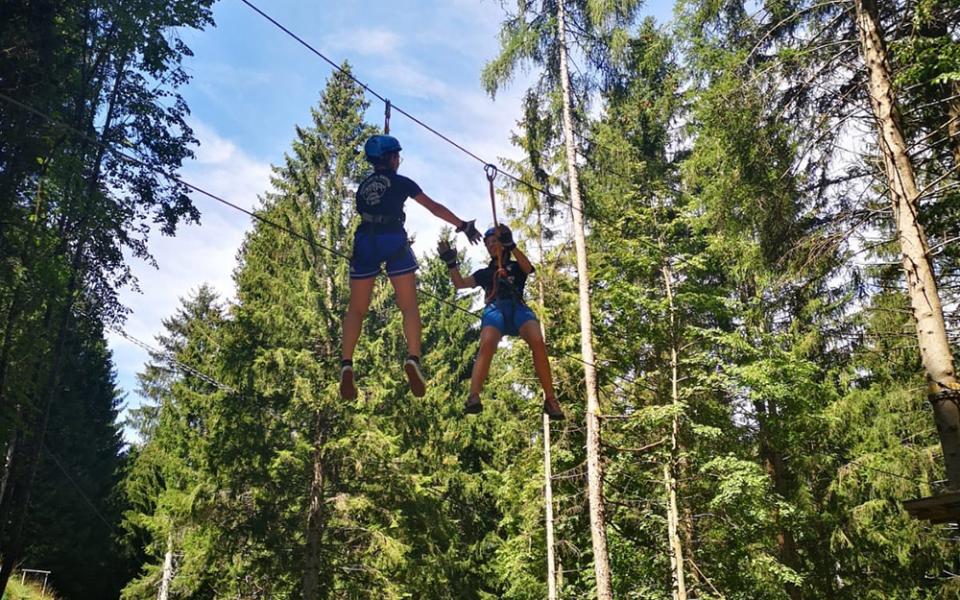 Due persone su una zipline tra gli alberi in una foresta.