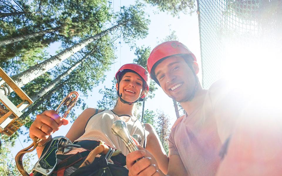 Due persone con caschi pronti per un'avventura all'aperto tra gli alberi.