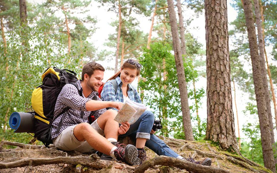 Due escursionisti consultano una mappa in una foresta, circondati da alberi.